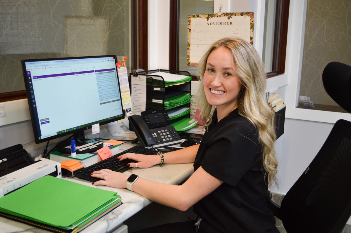 Nurse Mikha at the Fertility Wellness Institute sitting at a computer smiling